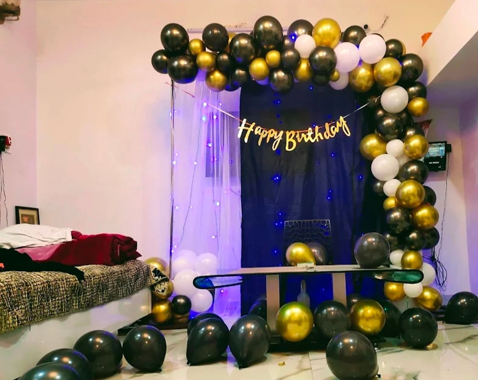 Birthday party decorations with black, gold, white balloons and a Happy Birthday banner.
