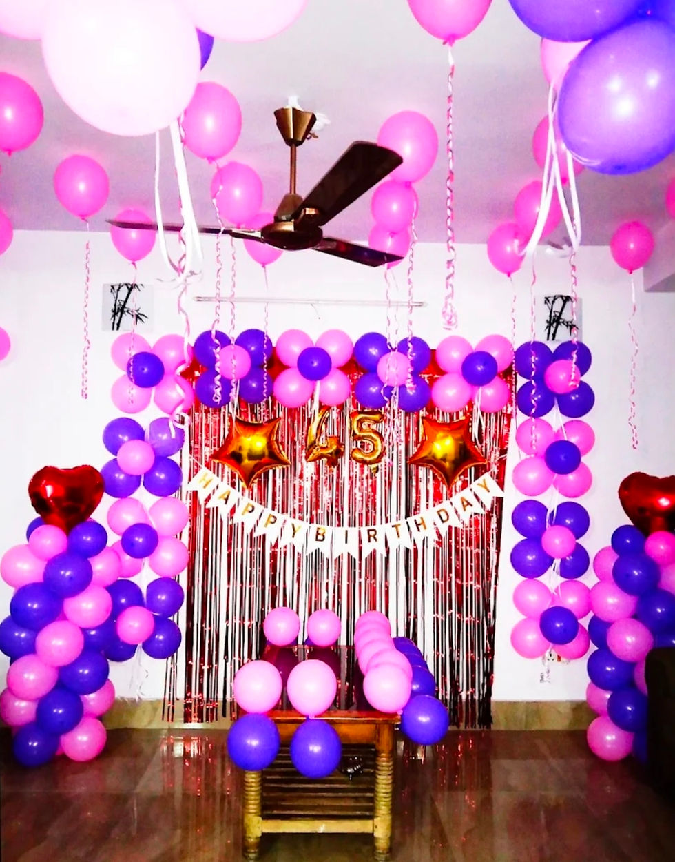 Birthday party decorations with pink and purple balloons and Happy Birthday banner.