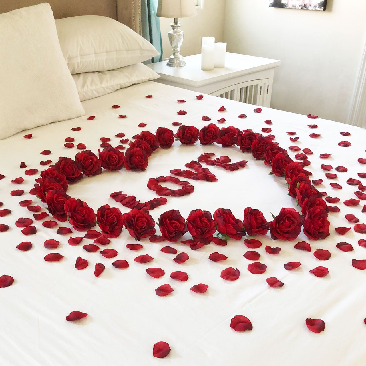 Red rose petals heart shape, LOVE text on white bed, romantic decor