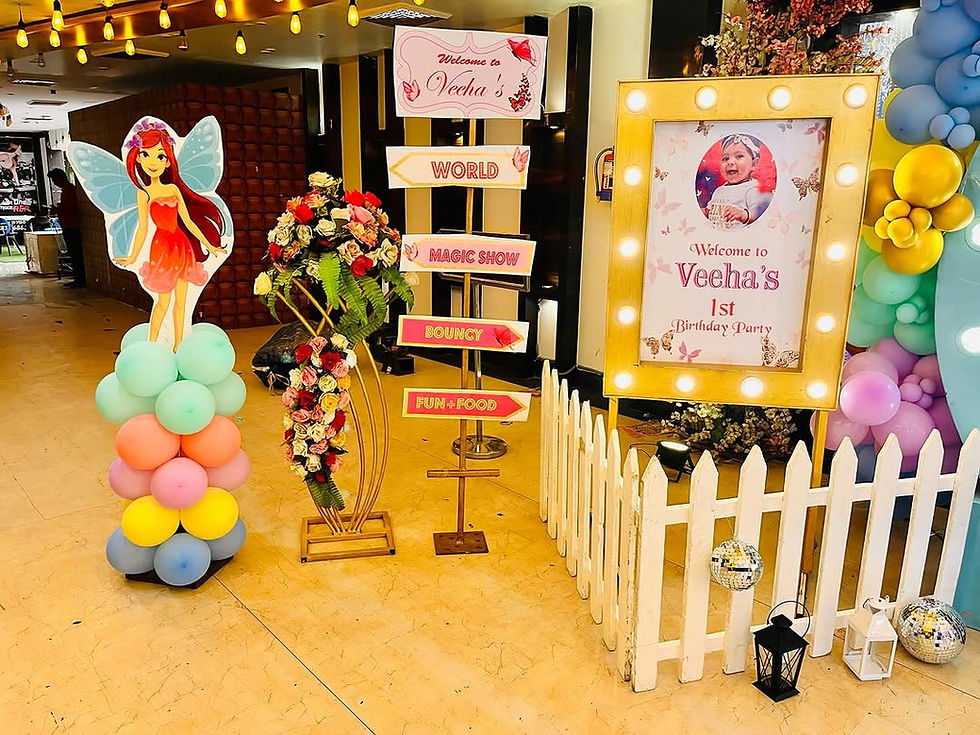 Thumbnail: Veena's 1st birthday event decor with signs, fairies, and party setup.