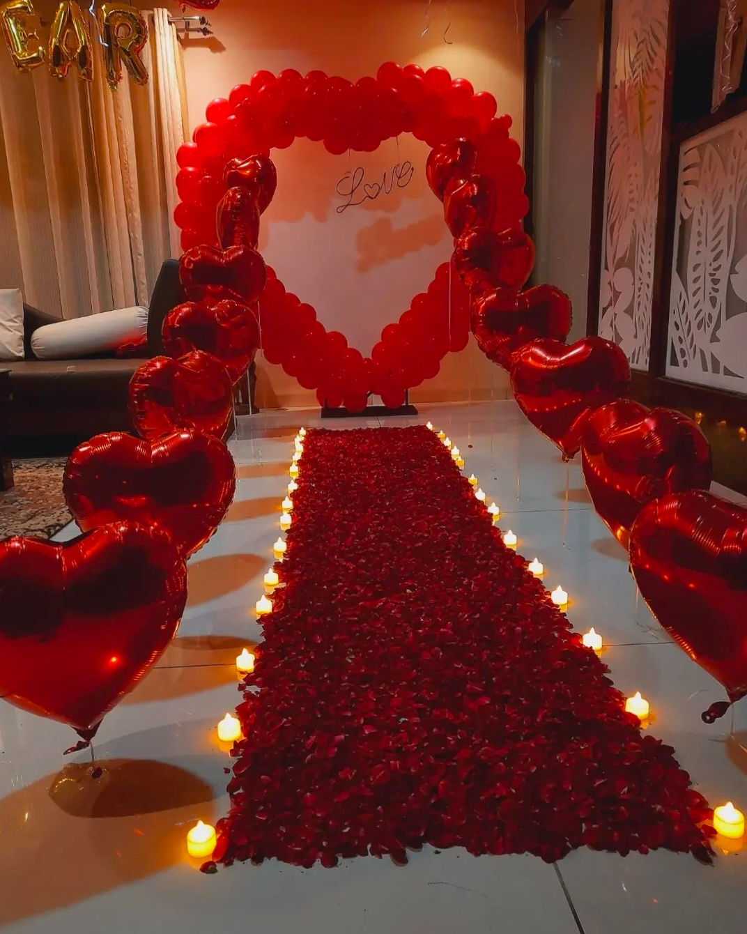Romantic red heart balloons and rose petals leading to an Oh Baby decor.