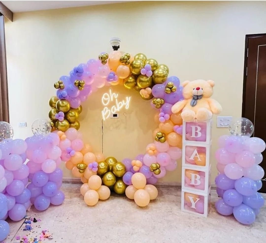 Oh Baby neon sign with colorful balloons, party decorations, and teddy bear.