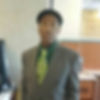 Mr. Bobby wearing a gray suit, green tie, and black newsboy hat.