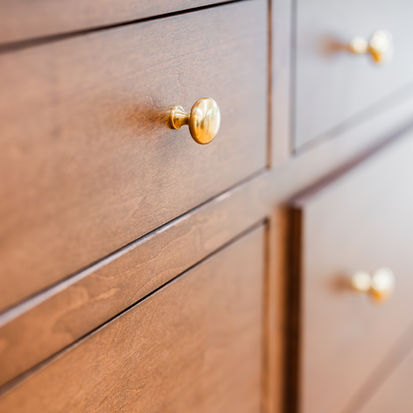 Close-up of wooden cabinet drawers with gold knobs