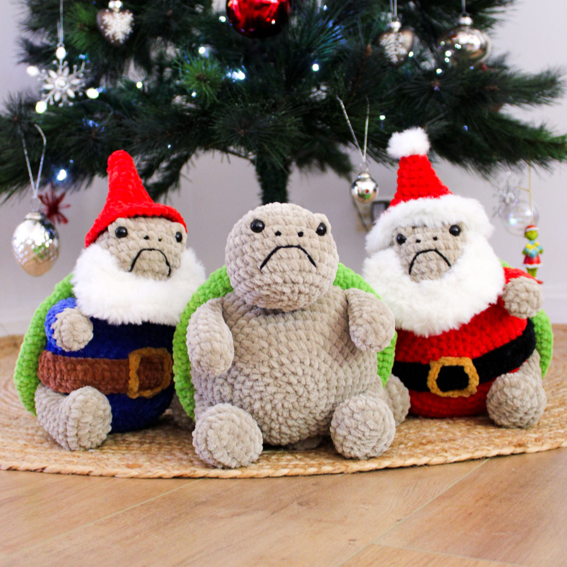 Three crocheted grumpy turtles, sitting together under a christmas tree.