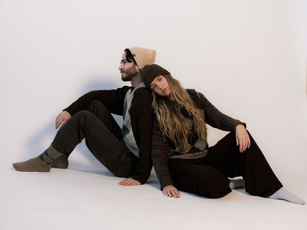 Two people sitting back to back in Revony beanies
