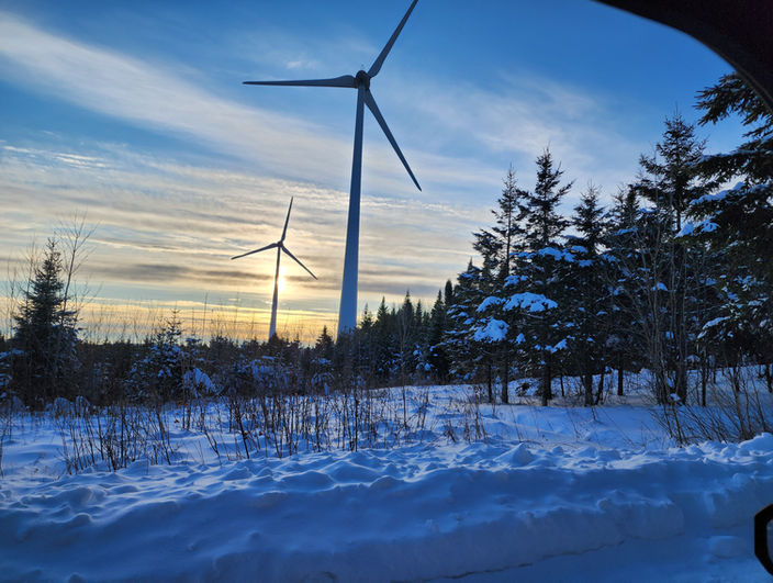 Mountain biking trail in winter in Quebec, overlooked by wind turbines