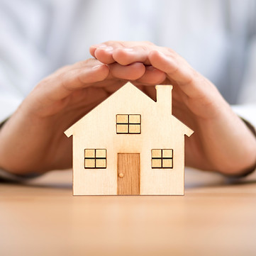 Wooden toy house protected by hands