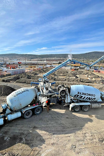 A picture showcasing two concrete mixture trucks on a construction site