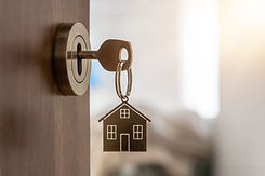 Open door to a new home with key and home shaped keychain