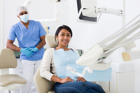 Cheerful hispanic female patient sitting in dental chair