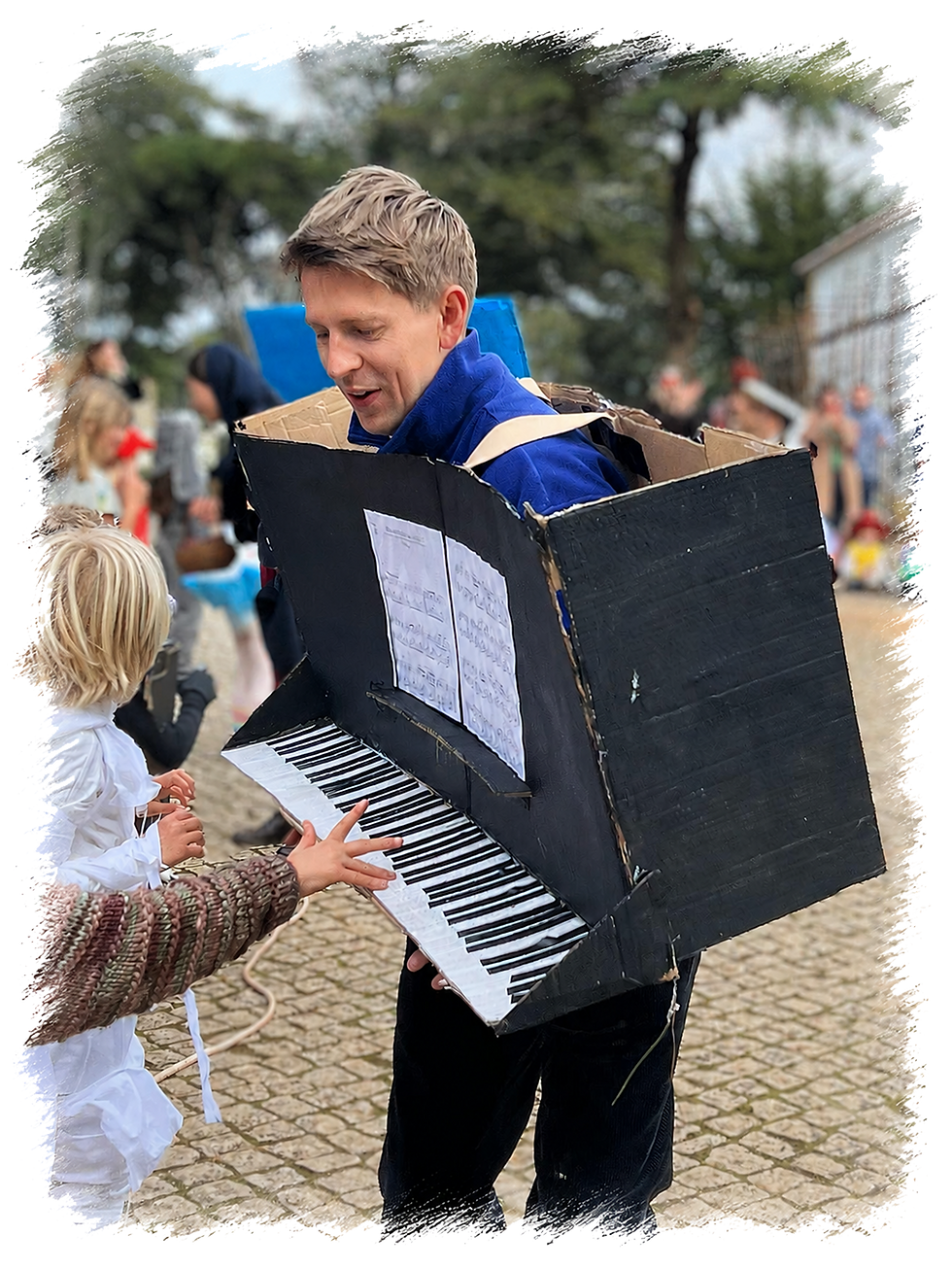 Smiling man in piano costume with child reaching for keys