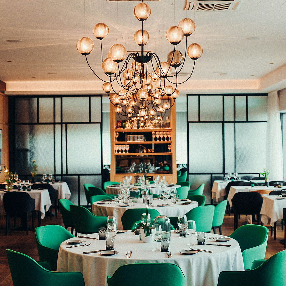 Elegant restaurant dining room with green chairs, white tables, and large chandelier.