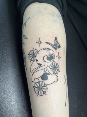 Tattoo of Stitch with flowers and a butterfly on the leg. Imagine of Ink 