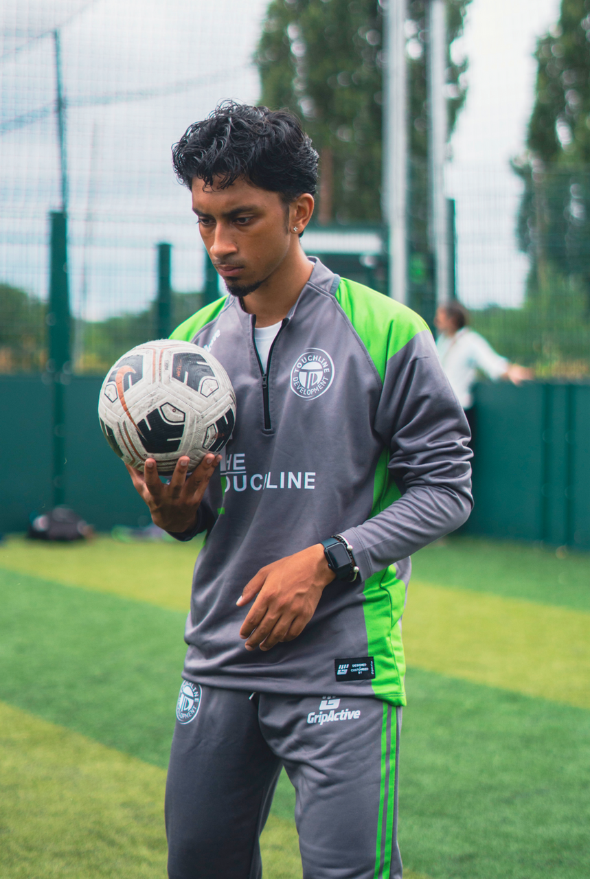 Coach showing proper kicking form and follow-through in a youth football training drill