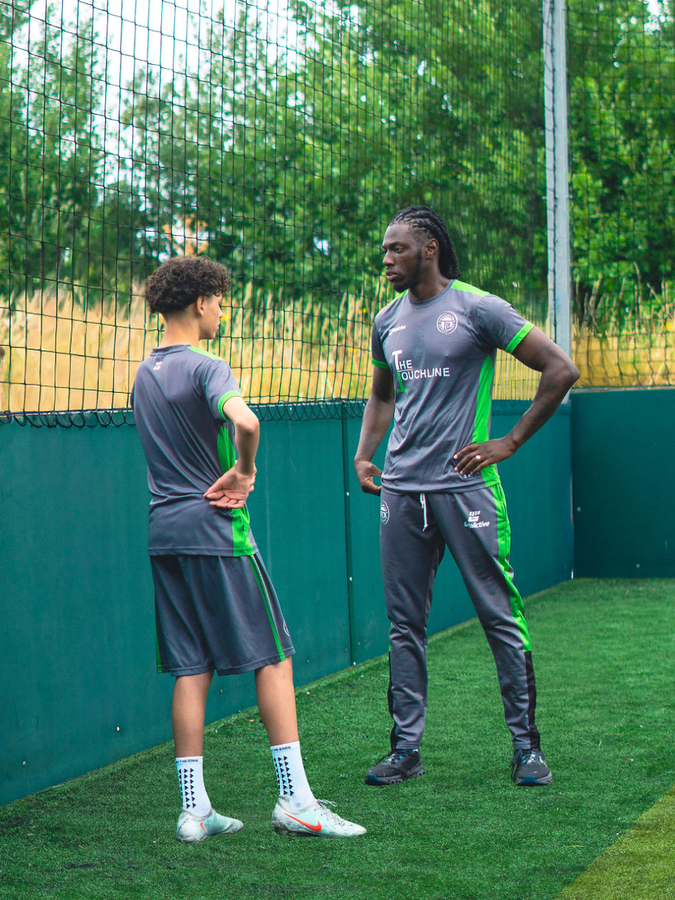 Adisa discusses technique and development with a young football player during an assessment.