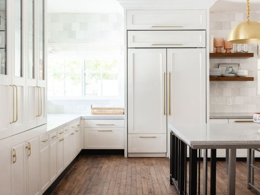 White, modern kitchen with gold hardware and a lot of natural light