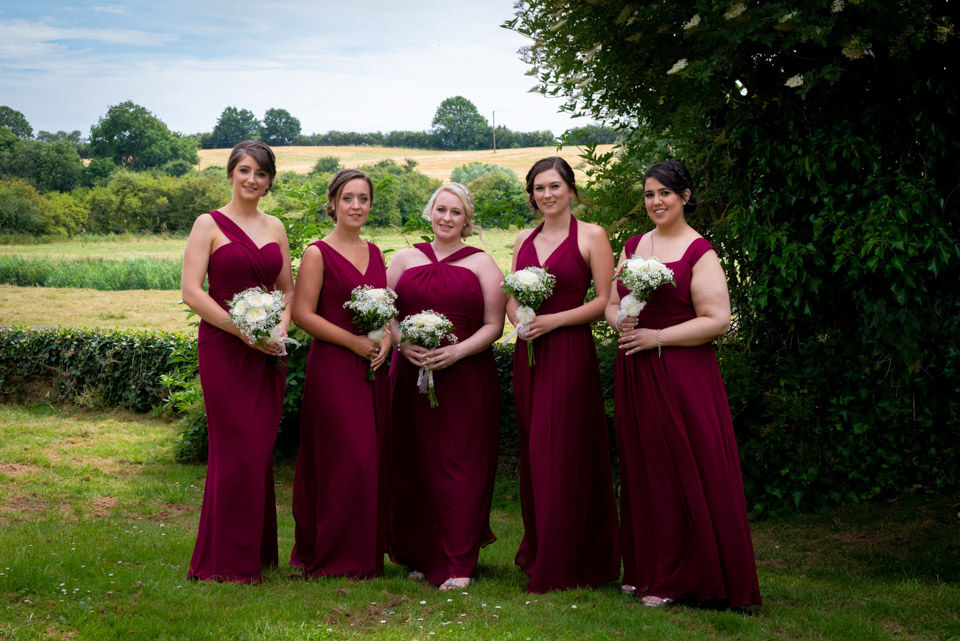 Elegant wedding photo of bridesmaids standing in a line, each holding a bouquet, showcasing a classy and timeless moment.