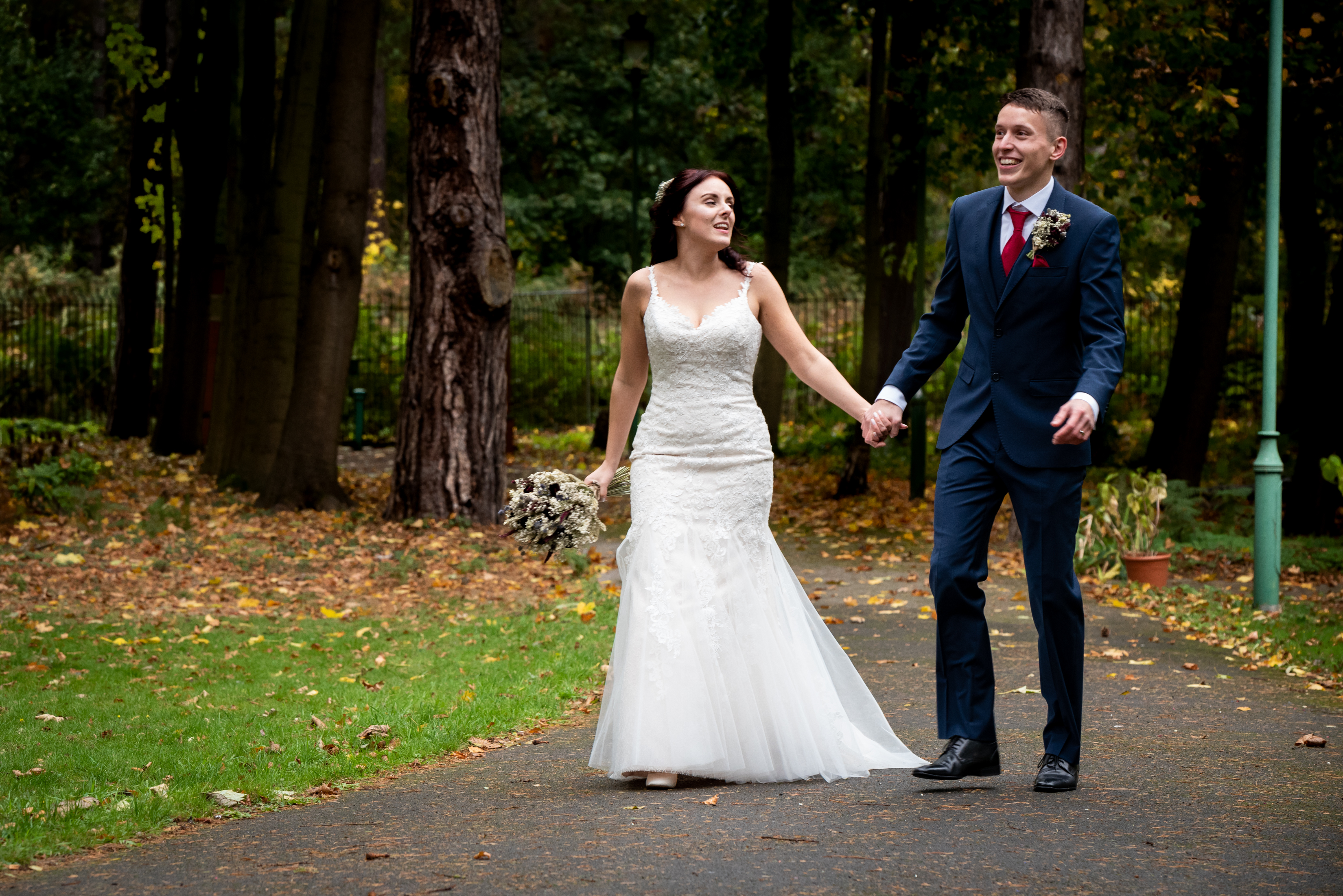 Bried and groom walking down a park footpath laughing