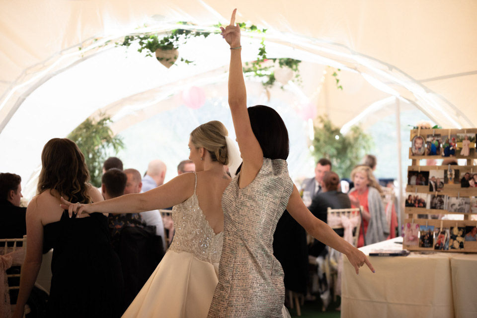 Fun and energetic moment of the bride having a dance-off with her best friend at the wedding, full of laughter and excitement.