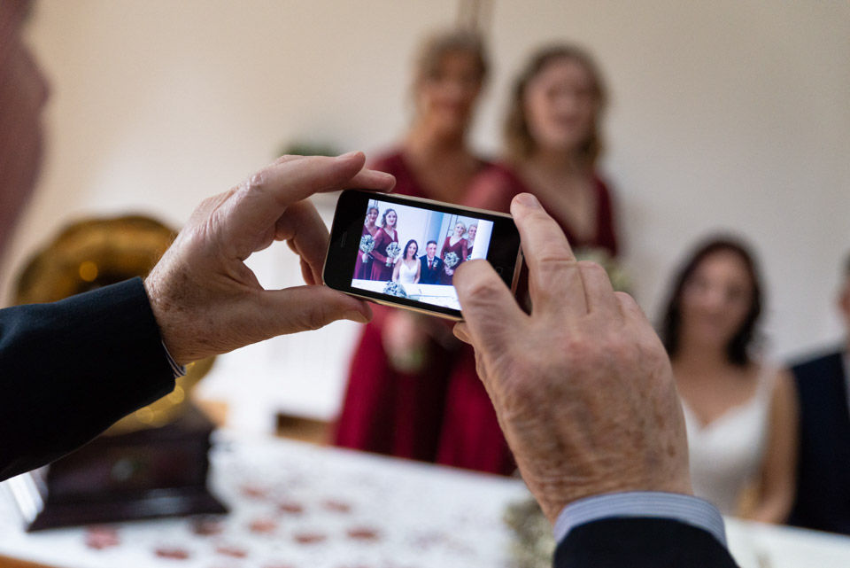 A guest at the wedding taking photos of the bridal party with his android phone