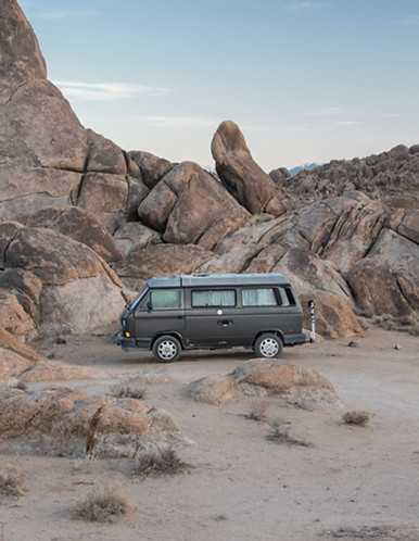 Blue caravan crossing a rocky desert landscape under a clear sky