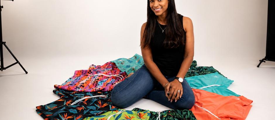 Sun Kulture founder Chandra Bogaerts sits in a white studio surrounded by the Original Sun Kulture l patterned shorts arranged in a circle.