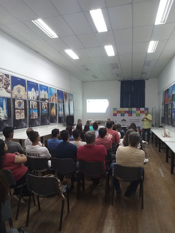 Vista de la sala durante la charla. El disertante, Juan Sebastián Mesples, ante un público atento en las instalaciones de la FAU-UCU. Al fondo, el banner institucional de la Universidad de Concepción del Uruguay.