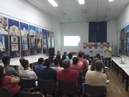 Vista de la sala durante la charla. El disertante, Juan Sebastián Mesples, ante un público atento en las instalaciones de la FAU-UCU. Al fondo, el banner institucional de la Universidad de Concepción del Uruguay.