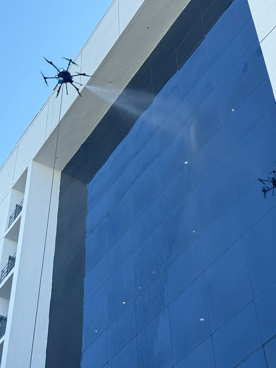 Drone window washing along reflective glass