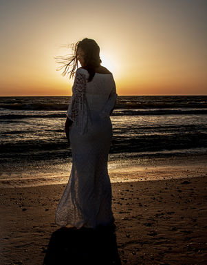 Silhouette of bride at beach. sunset.