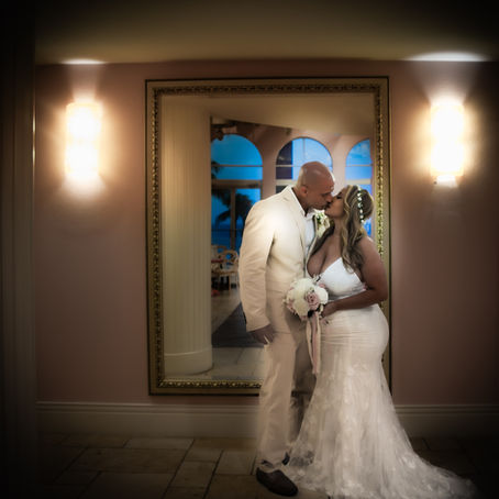 Bride and groom kissing in luxury indoor hallway after rain pivot at Florida beach wedding"