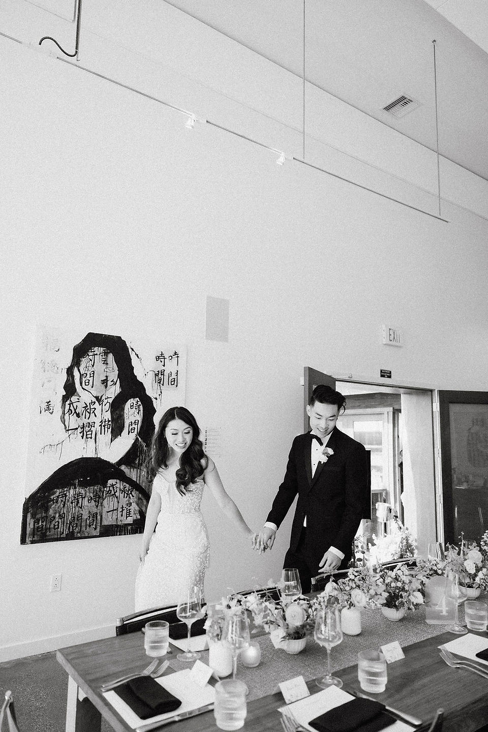 black and white photo of bride and groom walking and looking at the room called bride and groom walking into the modernism west gallery at the foreign cinema happy and surprised