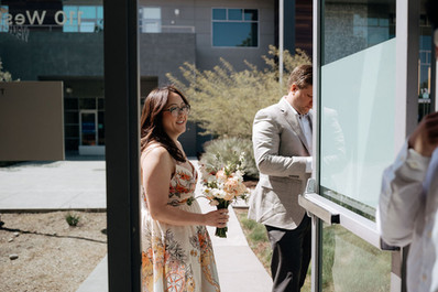 bride holding a bouquet while sombody is opening the door at san jose city hall