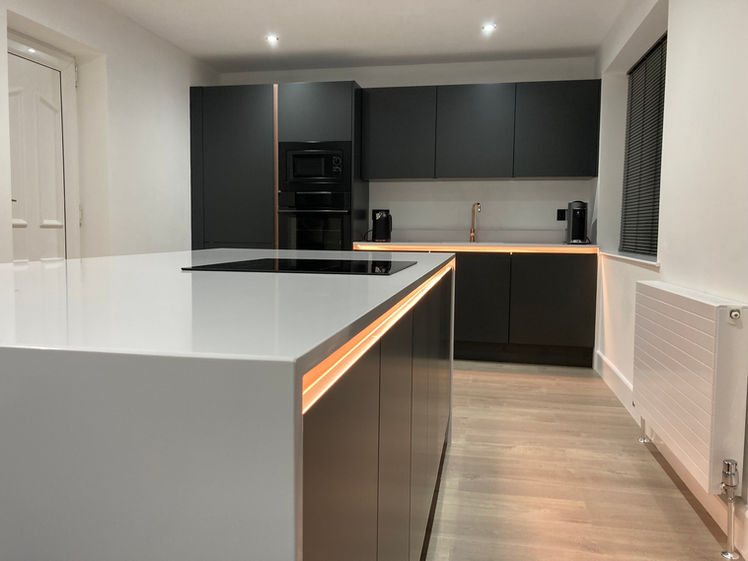new kitchen with black cupboards and island section with spot lights above