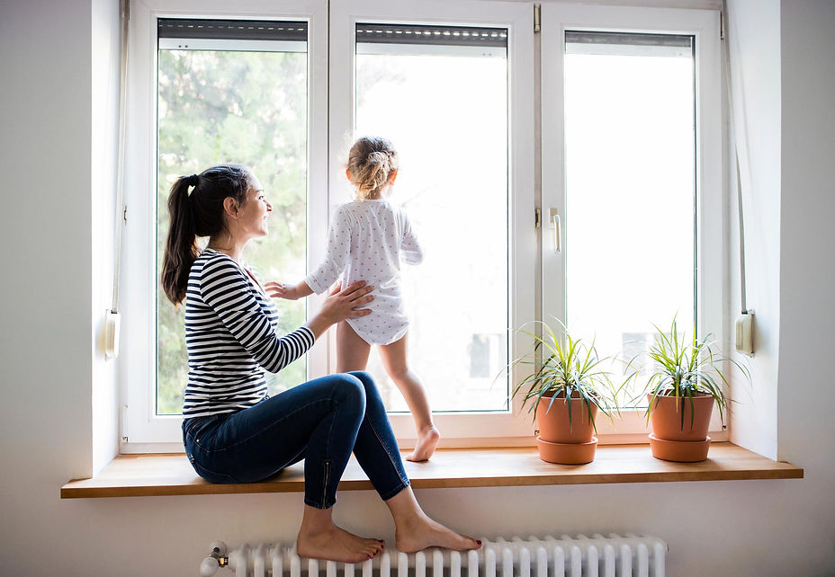 young mother sitting on window edge with her daughter