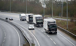A fleet of white moving transport trucks driving along a highway