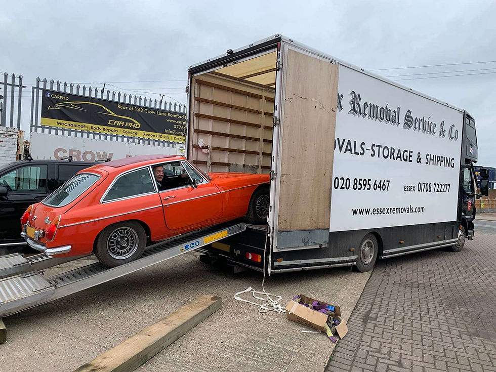 A bright red classic sports car being loaded into a container