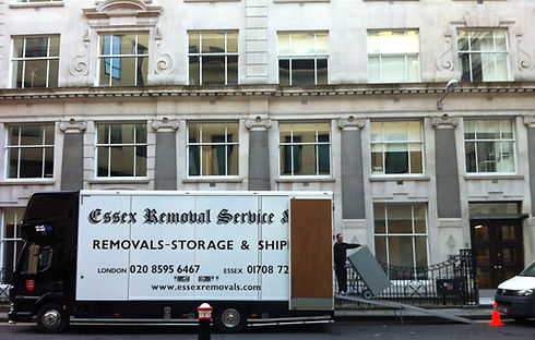 A black commercial moving truck parked beside an urban office block