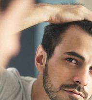 Un hombre se está revisando el cabello en un espejo.