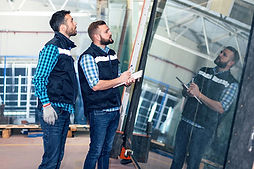Workers handling glass sheet in a warehouse