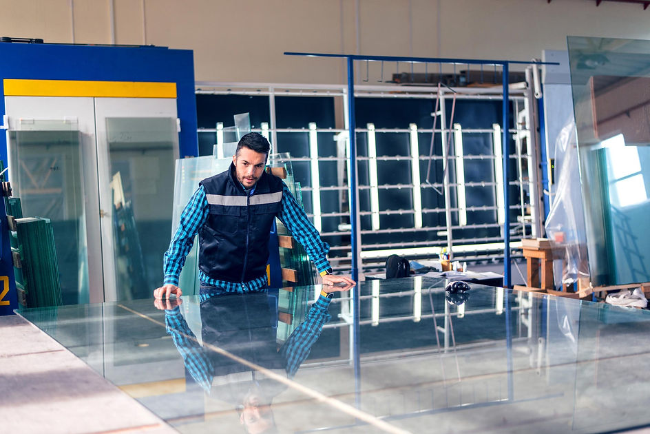 Worker handling glass sheet in warehouse
