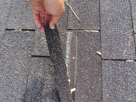 Roof shingle damage observed during a professional home inspection in South Metro Atlanta, showing lifted and deteriorated asphalt shingles.