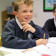 Smiling boy in school uniform at desk