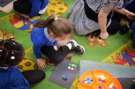 Child on rug sorting colorful shapes in nursery