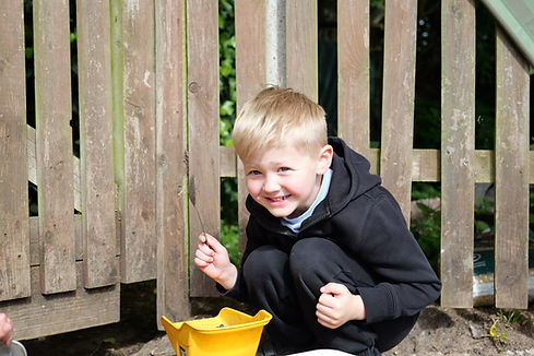 Smiling boy playing outdoors with a yellow bucket