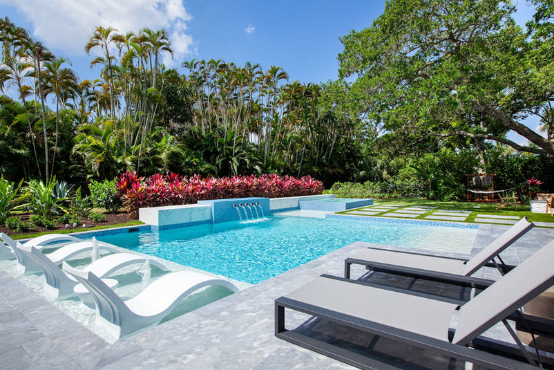 Luxury pool in Naples with sun shelf loungers, raised spa, and modern landscape design