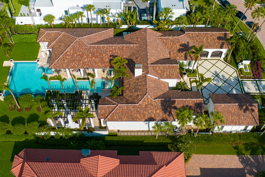 Aerial view of luxury estate renovation in Naples featuring infinity edge lap pool, spa, and tropical landscaping