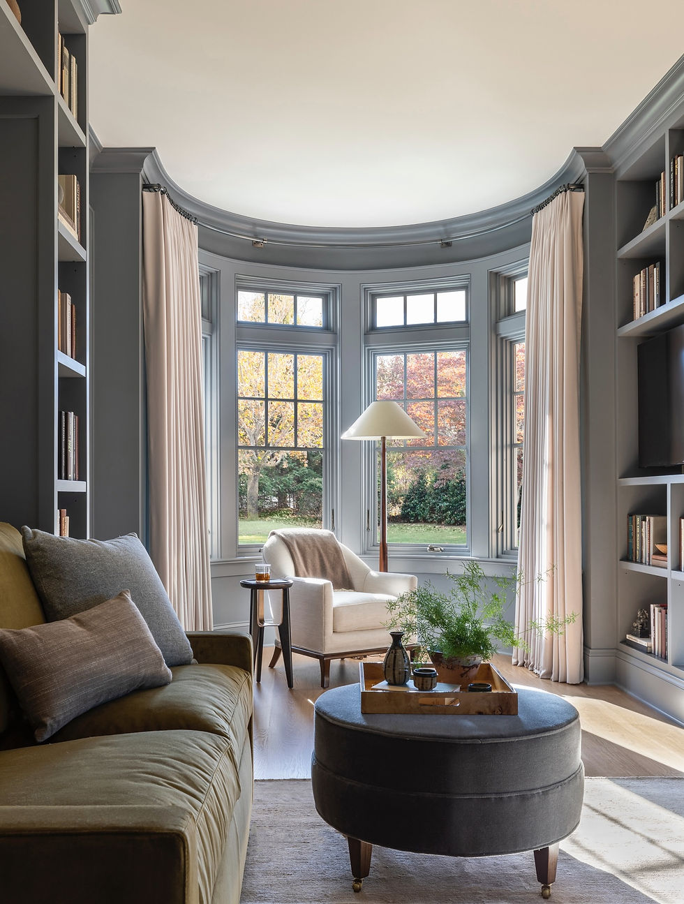 Elegant sitting room with custom built-in bookshelves, a curved bay window, and layered furnishings by Marie Flanigan Interio