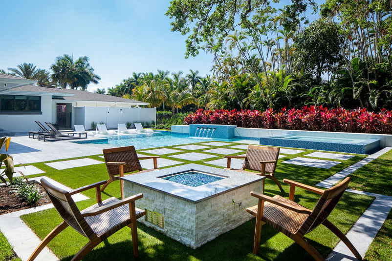 Luxury pool in Naples with sun shelf loungers, raised spa, and modern landscape design
